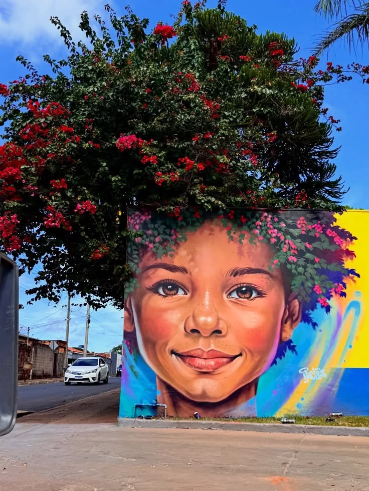 Colorful Medellín street mural of a young girl beneath flowering trees